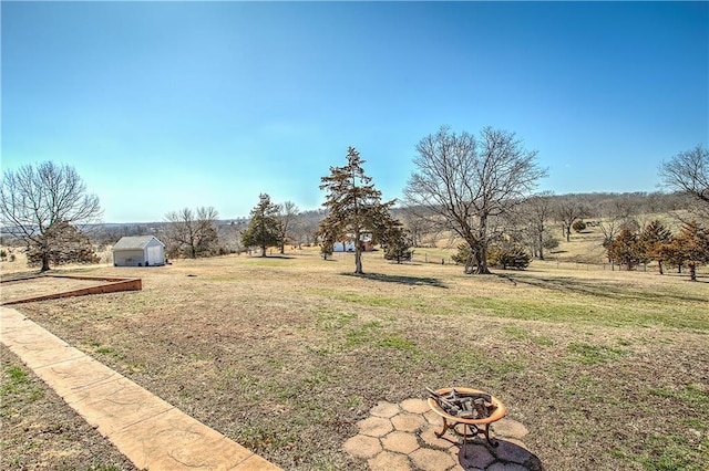 view of yard with a storage unit, a rural view, and a fire pit