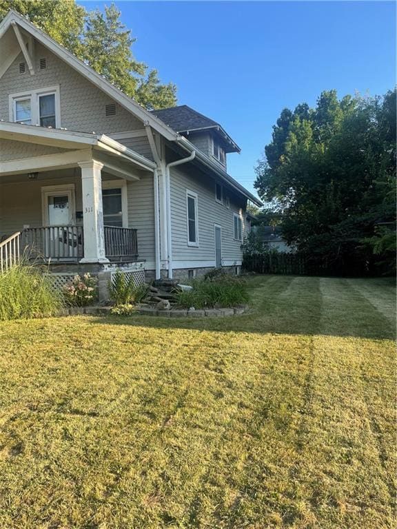 view of side of property with a porch and a yard