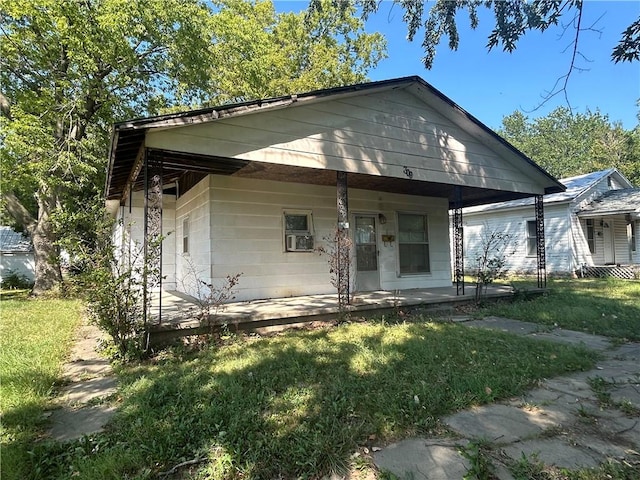 bungalow-style home featuring covered porch and a front yard