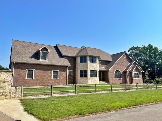 view of front of house featuring brick siding, a front yard, and a fenced front yard