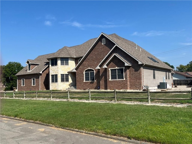 view of front of house with central AC and a front lawn