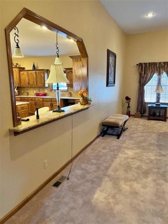 kitchen featuring kitchen peninsula, light colored carpet, and pendant lighting