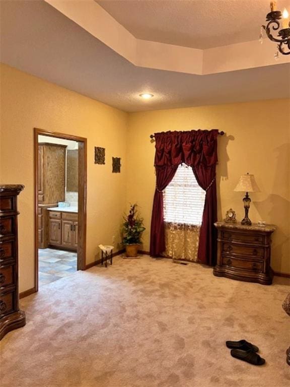 bedroom with carpet flooring, ensuite bath, and a tray ceiling