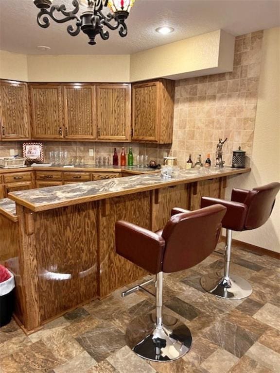 kitchen featuring kitchen peninsula, decorative backsplash, and a breakfast bar