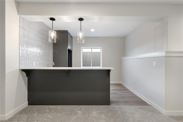 kitchen with pendant lighting, wood-type flooring, kitchen peninsula, and a kitchen bar