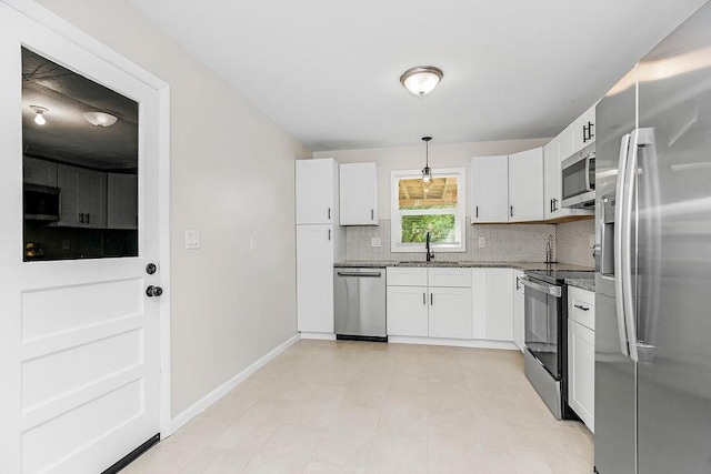 kitchen with light stone countertops, appliances with stainless steel finishes, backsplash, white cabinets, and hanging light fixtures