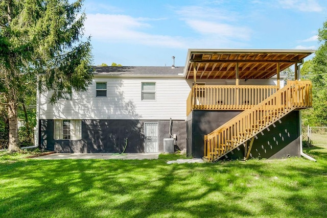 rear view of property featuring a yard, a wooden deck, and central AC