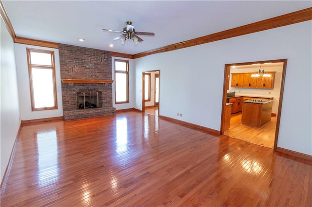 unfurnished living room with light hardwood / wood-style floors, ornamental molding, a wealth of natural light, and a fireplace