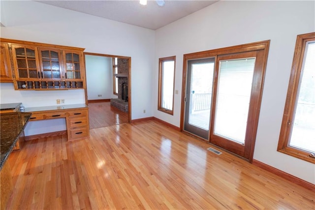 interior space with light hardwood / wood-style floors, a wealth of natural light, dark stone counters, and a fireplace