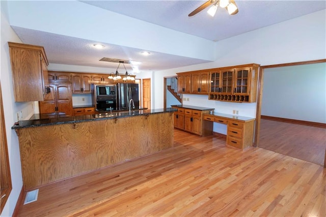 kitchen featuring kitchen peninsula, black appliances, light wood-type flooring, and pendant lighting