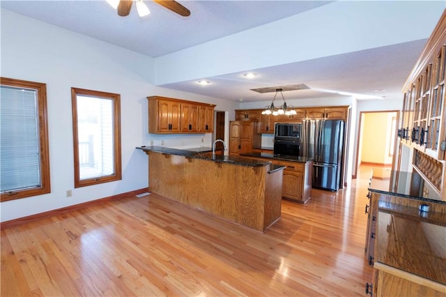 kitchen featuring a kitchen breakfast bar, black appliances, decorative light fixtures, light wood-type flooring, and ceiling fan with notable chandelier