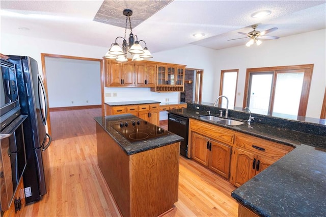 kitchen featuring a kitchen island, hanging light fixtures, sink, black appliances, and light wood-type flooring