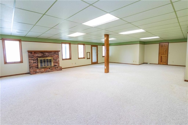 basement featuring a paneled ceiling, carpet, and a brick fireplace