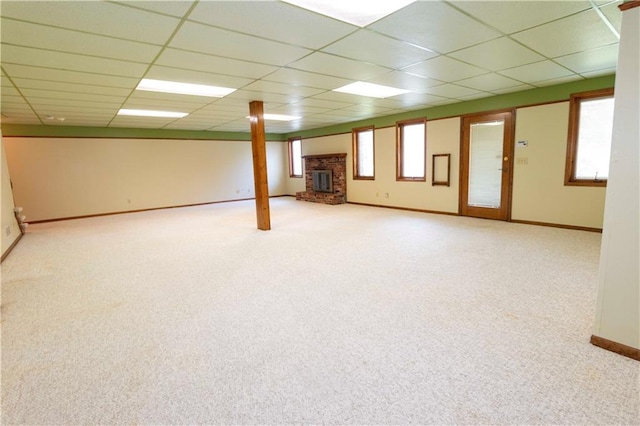 basement with light carpet, a drop ceiling, and a fireplace