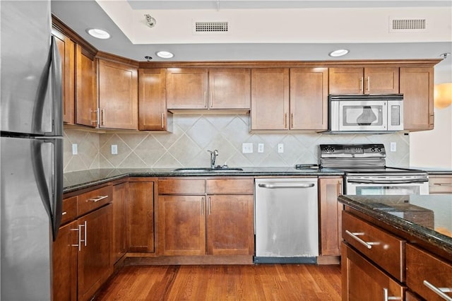 600 E Admiral Blvd Unit 704, Kansas City, MO 64106 - kitchen featuring appliances with stainless steel finishes, wood finished floors, dark stone countertops, backsplash, and recessed lighting