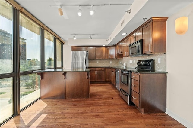 600 E Admiral Blvd Unit 704, Kansas City, MO 64106 - kitchen featuring appliances with stainless steel finishes, dark countertops, track lighting, dark wood-style floors, and backsplash