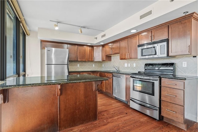 600 E Admiral Blvd Unit 704, Kansas City, MO 64106 - kitchen with stainless steel appliances, dark stone counters, dark wood-style floors, and backsplash