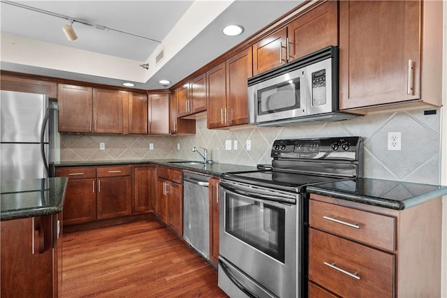 600 E Admiral Blvd Unit 704, Kansas City, MO 64106 - kitchen featuring appliances with stainless steel finishes, wood finished floors, dark stone counters, backsplash, and rail lighting
