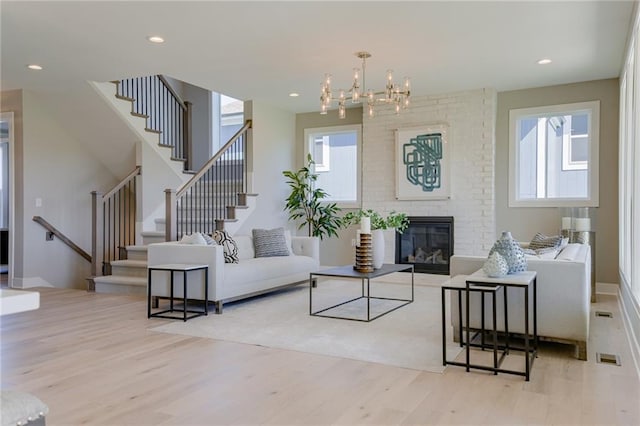 living room with a chandelier, a fireplace, and light hardwood / wood-style floors