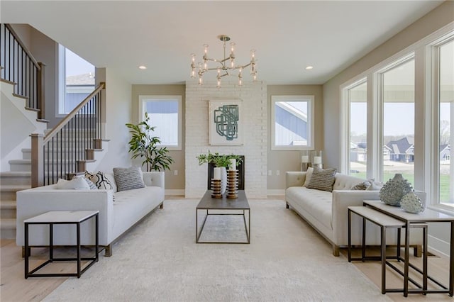 living room featuring light hardwood / wood-style flooring, a large fireplace, an inviting chandelier, and a healthy amount of sunlight