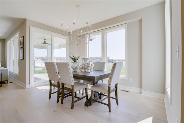 dining space featuring a wealth of natural light, ceiling fan with notable chandelier, and light hardwood / wood-style floors