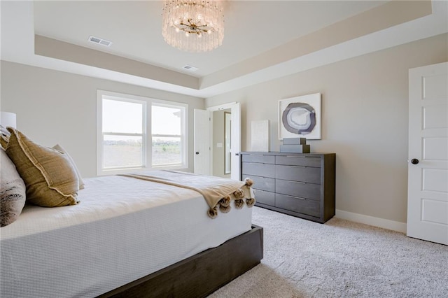 carpeted bedroom featuring a tray ceiling and a chandelier