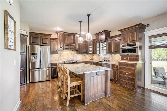 kitchen with a kitchen island, pendant lighting, dark wood-type flooring, and stainless steel appliances