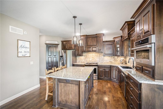 kitchen with sink, decorative light fixtures, stainless steel appliances, dark hardwood / wood-style floors, and a center island