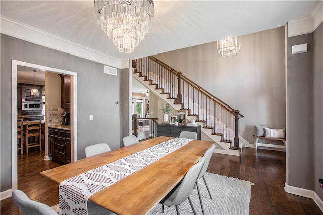 dining space with an inviting chandelier, crown molding, and dark hardwood / wood-style flooring