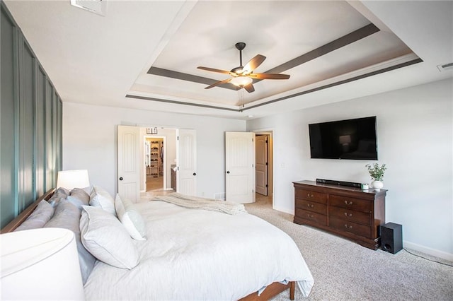 bedroom with light carpet, ceiling fan, and a raised ceiling