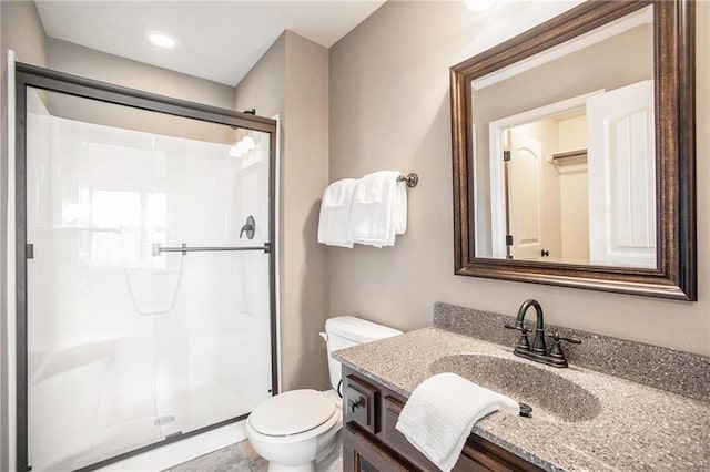 bathroom with vanity, a shower with shower door, and toilet