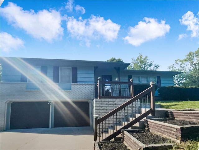 7227 Greeley Ave, Kansas City, KS 66109 - view of front of home with stairs, concrete driveway, a garage, and brick siding