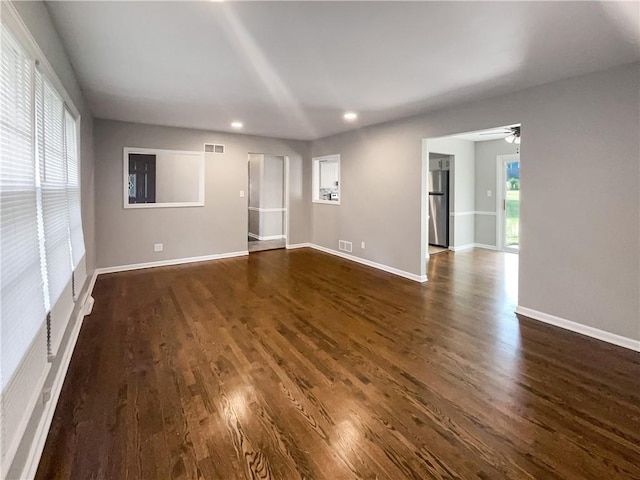 unfurnished room featuring plenty of natural light, ceiling fan, and dark hardwood / wood-style floors