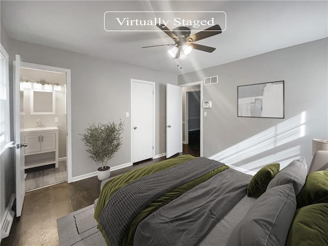 bedroom with visible vents, dark wood-type flooring, a sink, ensuite bath, and baseboards