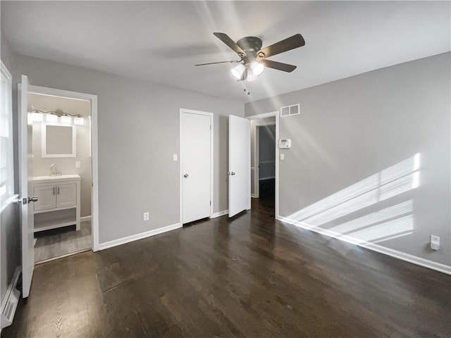 unfurnished bedroom featuring dark wood finished floors, baseboards, visible vents, and a sink