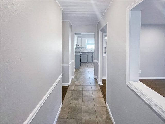 corridor featuring tile patterned floors, crown molding, and baseboards