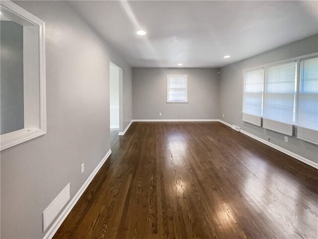 empty room with recessed lighting, visible vents, baseboards, and dark wood finished floors