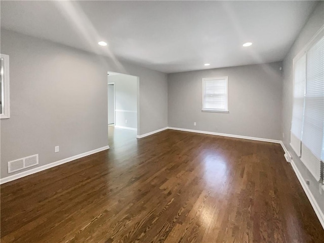 empty room with visible vents, recessed lighting, baseboards, and dark wood-style flooring