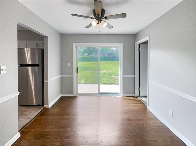 unfurnished dining area with ceiling fan, baseboards, and wood finished floors