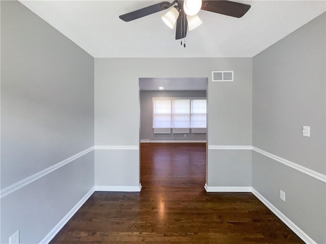 spare room with a ceiling fan, wood finished floors, visible vents, and baseboards