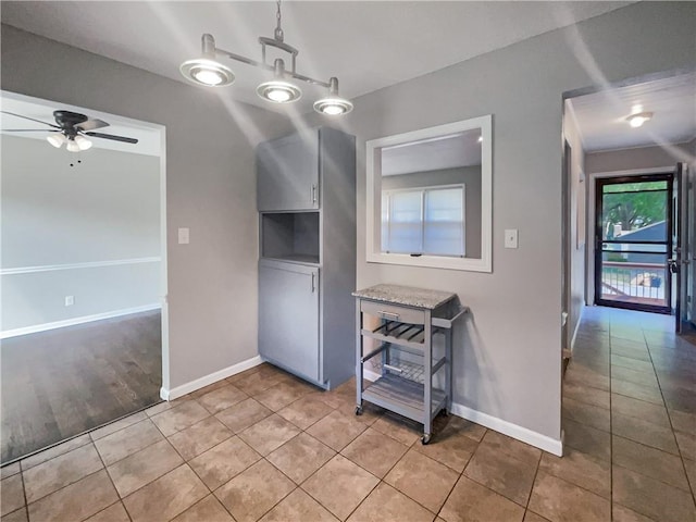 unfurnished dining area with light tile patterned floors, a ceiling fan, and baseboards