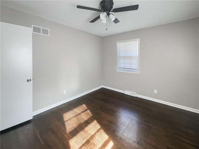 empty room featuring visible vents, a ceiling fan, dark wood-type flooring, and baseboards