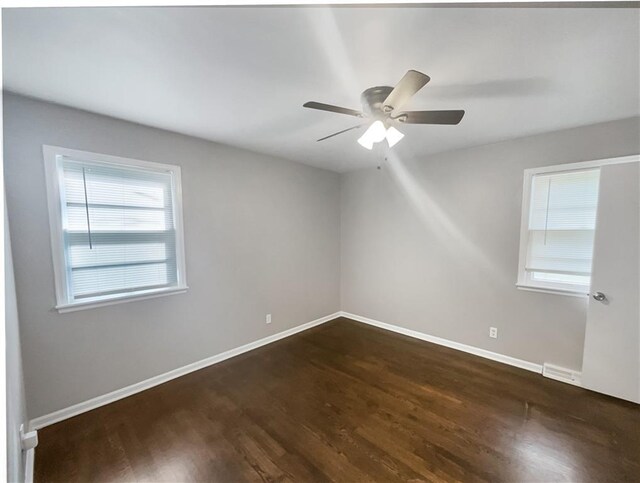 empty room with visible vents, a ceiling fan, dark wood-type flooring, and baseboards