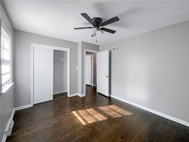 unfurnished bedroom featuring visible vents, baseboards, a closet, a ceiling fan, and dark wood-style flooring