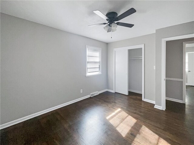 unfurnished bedroom featuring visible vents, baseboards, a closet, and dark wood-style floors