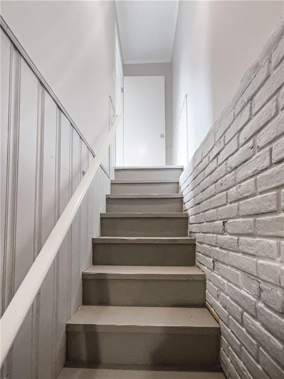 staircase featuring brick wall