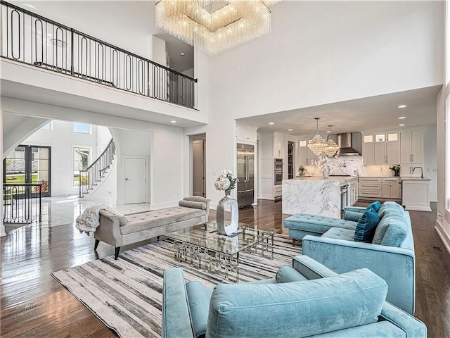 living room with a high ceiling, dark hardwood / wood-style floors, a chandelier, and sink