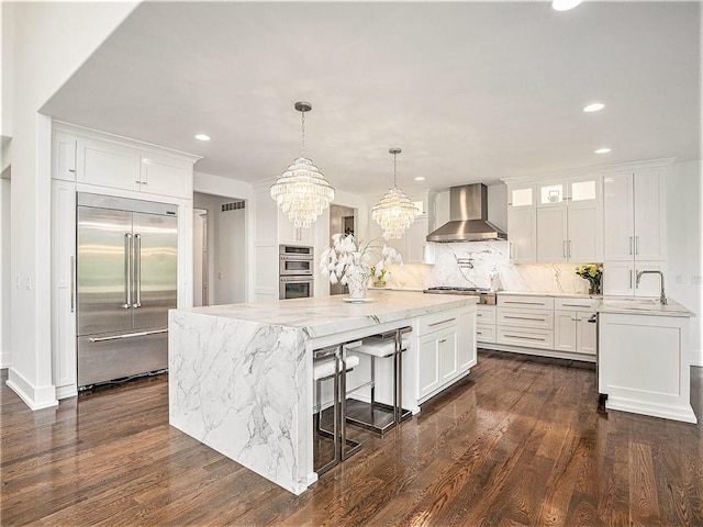 kitchen featuring appliances with stainless steel finishes, dark hardwood / wood-style floors, wall chimney range hood, and white cabinets