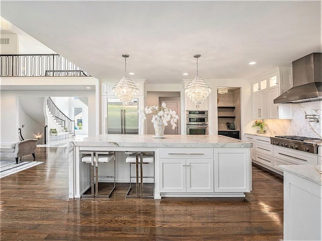 kitchen with appliances with stainless steel finishes, dark hardwood / wood-style floors, wall chimney range hood, and white cabinetry