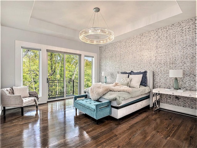 bedroom featuring multiple windows, a raised ceiling, and dark hardwood / wood-style flooring